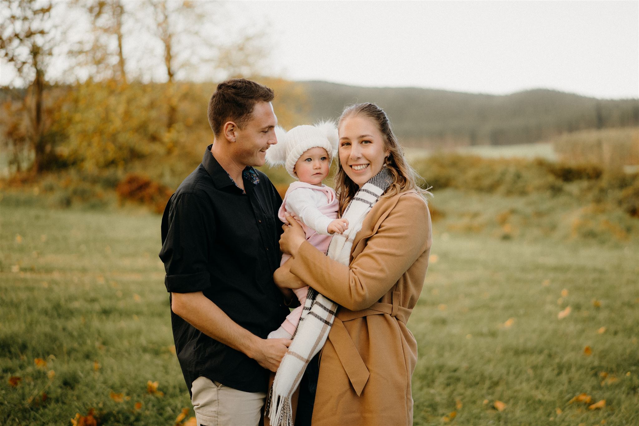 a photo of a family together holding a little baby during their sunset family photoshoot in Waikato photographed by Tashina Narelle Photography