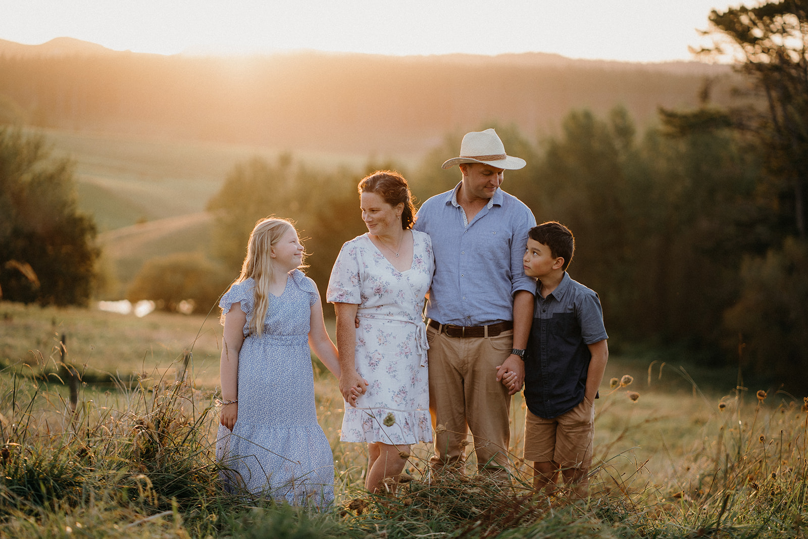 A Family stands on a hill in Wellsford during their sunset photoshoot by Tashina Narelle Photo + Video