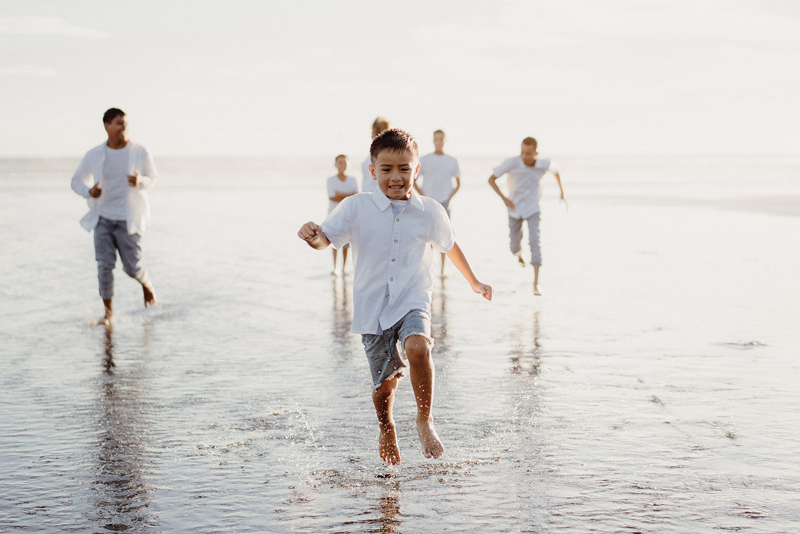 A boy jumps in the sea water at Kariotahi Beach during his Family photoshoot with Tashina Narelle Photo + Video